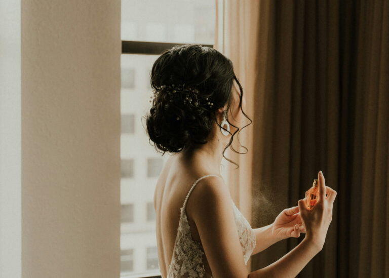 A glamourous woman spritzing perfume on herself